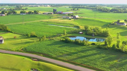 Stunning Summer evening flyover of lush green rural Midwest farmlands.
