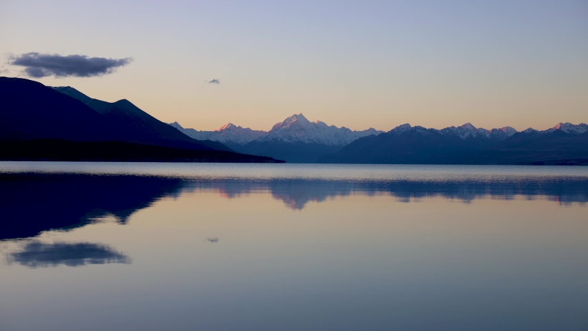 Wide sunset time lapse of Mount Cook and Lake Pukaki with reflections of bright clear mountain skyline. Mount Cook National park, Lake Pukaki, Mackenzie country, New Zealand