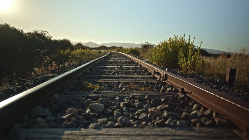 Golden sunrise across deserted train tracks in a rural setting. Low angle.