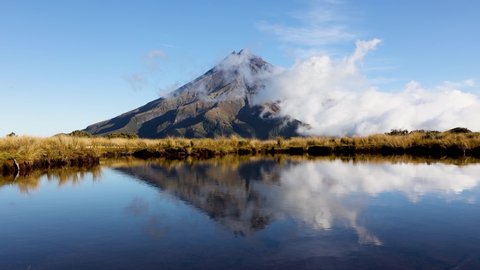 Beautiful sunset Timelapse of clouds rolling around base of Mount Taranaki. Shot with reflection from the Pouakai tarns on Mangorei track in New Plymouth, New Zealand