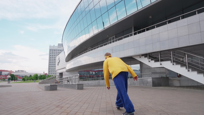 Free running, young man runs over obstacles in the city and doing a flips on training area near modern buildings, 4k slow motion.