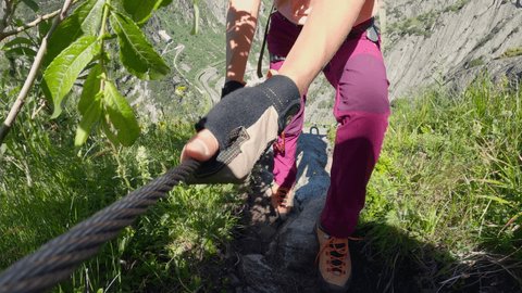 Young woman rock climbing on Alpine route. Female wearing climbing equipment reaches mountain's top