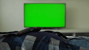 Man is asleep, the remote control from TV is lying on his stomach. Slumber. Green screen chromakey. Sleep. Fatigue, weariness. Guy is lying on sofa in room at home and not watching TV