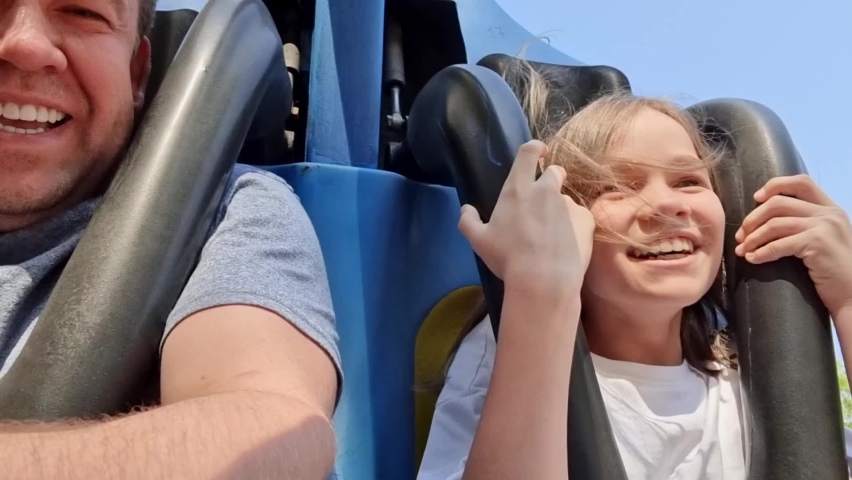 Dad and daughter ride an extreme attraction. adrenaline and fun in the amusement park. roller coaster. carousels and swings. bright emotions. family weekend. | Shutterstock HD Video #1075599281