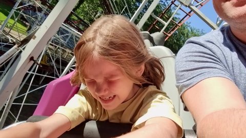 dad and daughter ride an extreme attraction. adrenaline and fun in the amusement park. roller coaster. carousels and swings. bright emotions. family weekend.