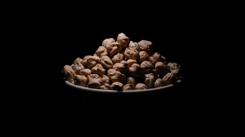 Chickpeas or garbanzos beans in a bowl gyrating on black background