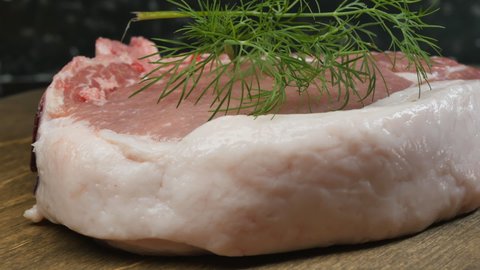 Detail.Fresh raw fatty pork entrecote with green dill. Dolly shot. Close-up.
