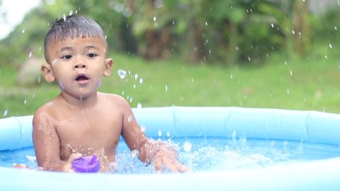 Kids having fun, playing in water in inflatable pool at home.