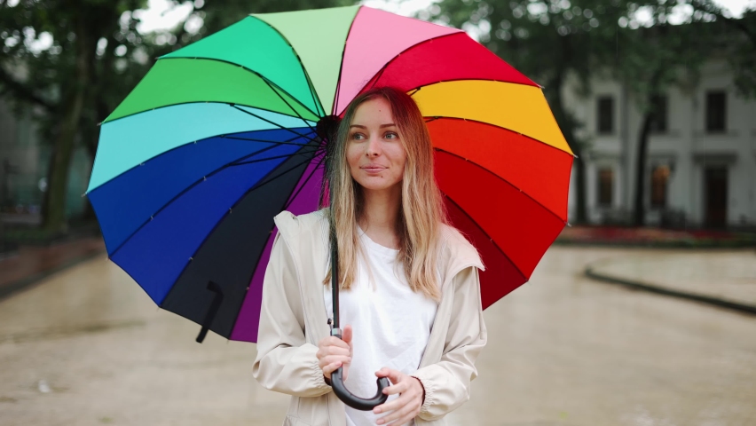 Portrait of a woman spinning multi-colored umbrella on the street