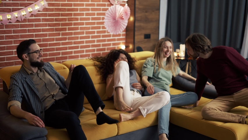 Four people in living room on sofa together having fun, fighting