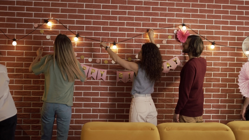 Diverse people preparing party indoors, decorating living room