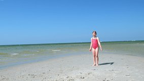4K 60 fps video of active beautiful child girl having fun making acrobatic wheel on beautiful beach on summer holidays