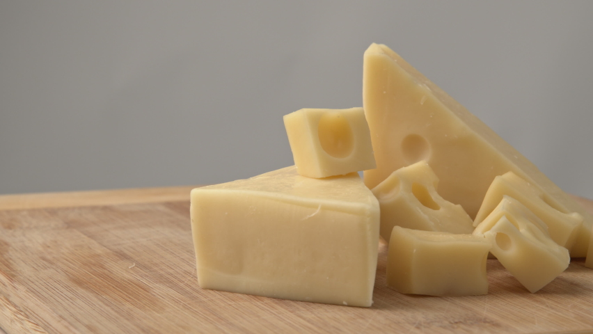Cheese cubes rotating. close up. Yellow diced cheese is rotating on a wooden plate. Cubes of cheese. Triangles of goat milk cheese. Pieces of different cheeses on plate. Royalty-Free Stock Footage #1075606445