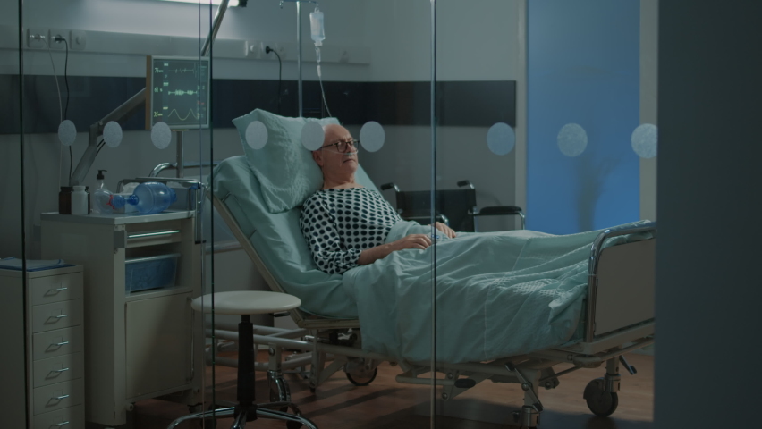 Sick patient sleeping in hospital ward bed at health facility with nasal oxygen tube for breathing problems. Old man with disease waiting for medical treatment to recover from illness | Shutterstock HD Video #1075611179