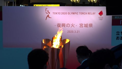 SENDAI, MIYAGI, JAPAN - 21 MARCH 2020 : Olympic Flame displayed at Sendai station. Crowd of people wearing masks. Tokyo Olympic 2020 have been postponed to 2021 due to coronavirus.