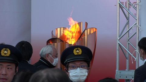 SENDAI, MIYAGI, JAPAN - 21 MARCH 2020 : Olympic Flame displayed at Sendai station. Crowd of people wearing masks. Tokyo Olympic 2020 have been postponed to 2021 due to coronavirus.