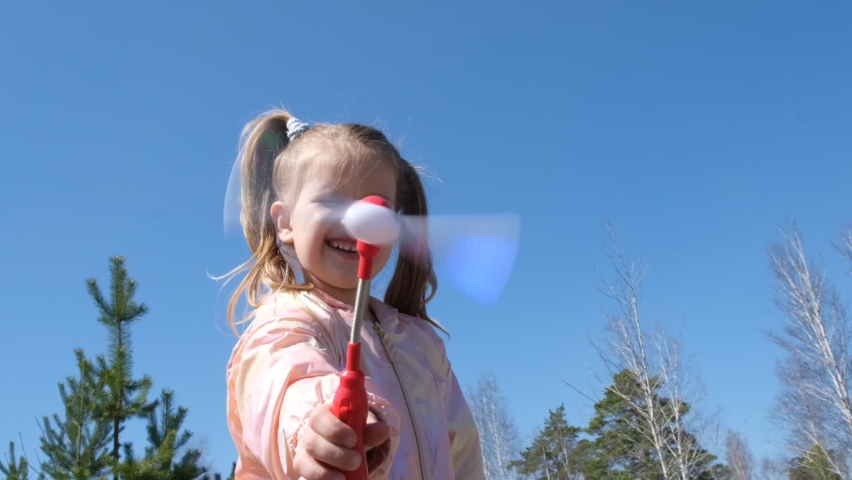 Child playing with pinwheel . Little girl having fun with electric turbine toy. Outdoor kids activity concept 