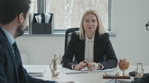 PAN medium shot of confident female executive of law company having meeting with professional team of lawyers at conference table in modern office