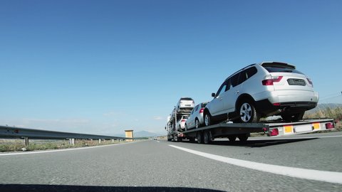 A large tow truck car transporter delivers used cars driving on highway