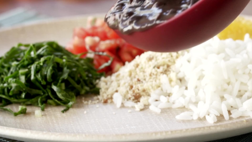 Putting feijoada on a plate in slow motion. Traditional Brazilian food Royalty-Free Stock Footage #1075621700