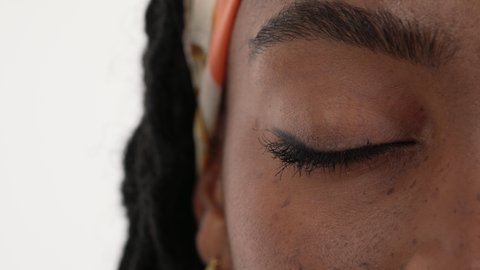 Close up of an African woman's eye. Showing her right eye closed and then slowly opening, looking to the camera