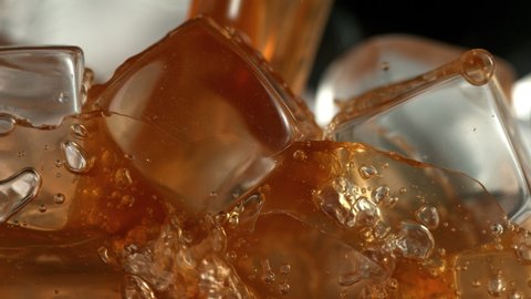 Super Slow Motion Detail Shot of Pouring Ice Coffee into Glass with Ice Cubes at 1000 fps.