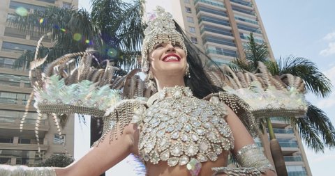 Beautiful Brazilian woman wearing colorful Carnival costume and smiling during Carnaval street parade in city. 4K.