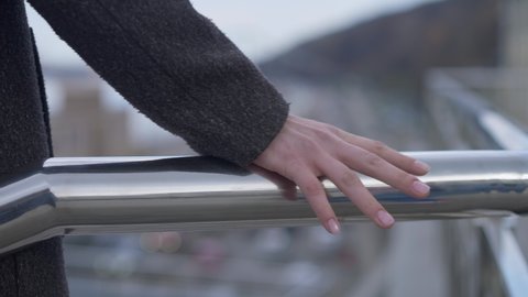 Female hand holding bridge handrail with blurred road at bottom. Unrecognizable young Caucasian suicidal woman attempting jump down. Suicide and crisis concept