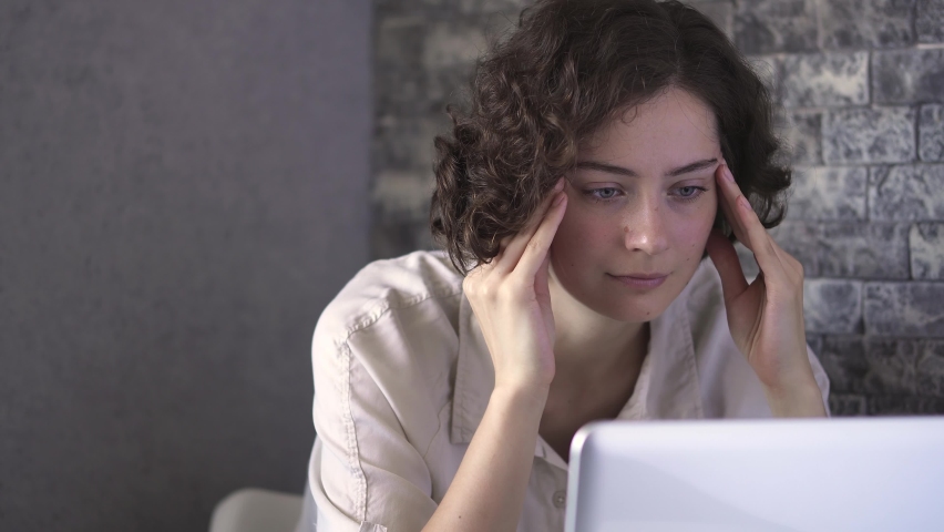 Young woman tired human under stress near laptop monitor. Feeling tired, tension headache, sadness, sad mood. Signs of depression, discouragement, and despondency. Hard to work. Feel stress.
 | Shutterstock HD Video #1075632602