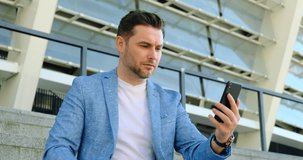 Young Man Using Smartphone on City Street. a Man talking via video link with a girl on a Dating Site, Businessman Communicates via Videoconference with a Business Partner about a Successful Deal