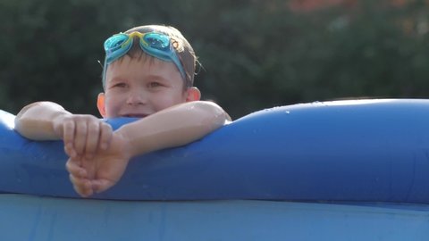 Pleasant wet male kid in goggles relaxing at inflatable rubber swimming pool spending time at luxury resort enjoying happy childhood and summer travel vacation cute baby boy resting