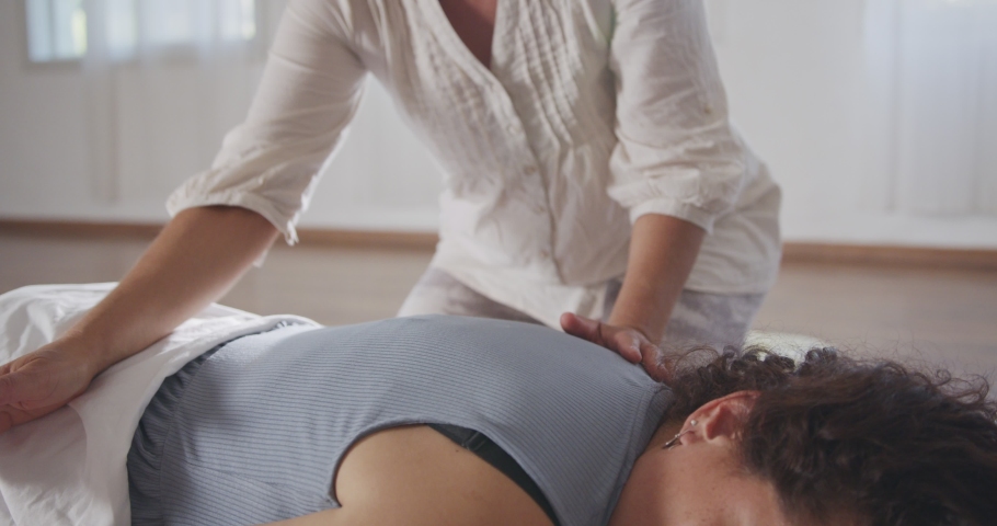 Shiatsu treatment. Masseuse pressing and massaging the back and the shoulders of woman Royalty-Free Stock Footage #1075648628