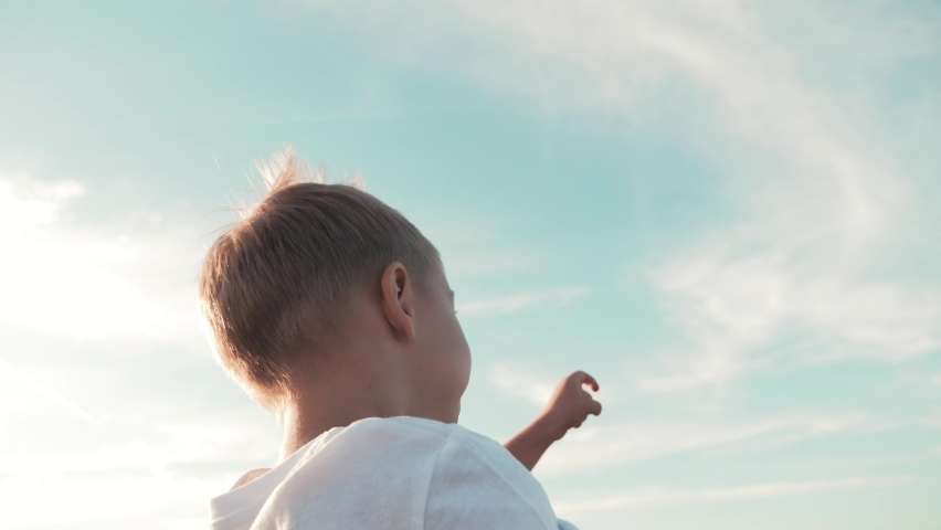 Lovely cute boy having fun outdoors. Boy pointing hand to blue sky. Happy family at sunset. Royalty-Free Stock Footage #1075654871