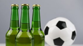 A soccer ball is spinning next to three bottles of beer on a white background