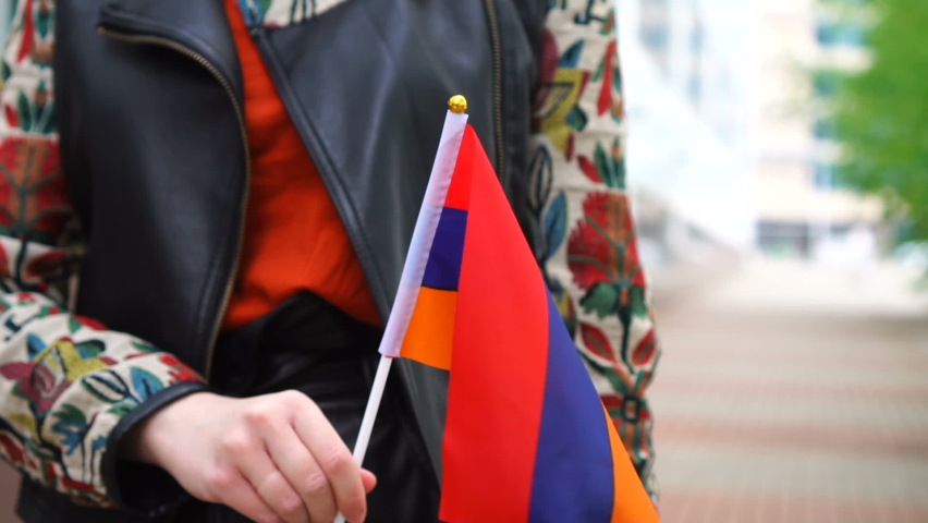 Unrecognizable woman holding Armenian flag. Girl walking down street with national flag of Armenia Royalty-Free Stock Footage #1075655951