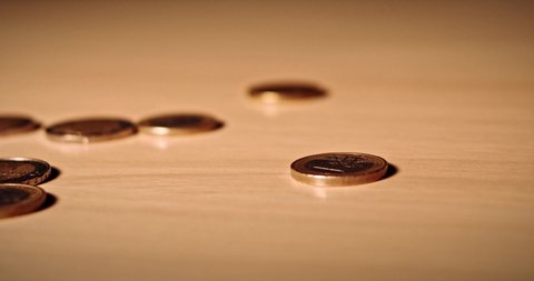 1 euro spinning top coin. One spanish euro coin spinning on a table. Wealth, investment and money. Close up of a single coin that stops spinning in focus between other coins. Slow motion video in 4k.