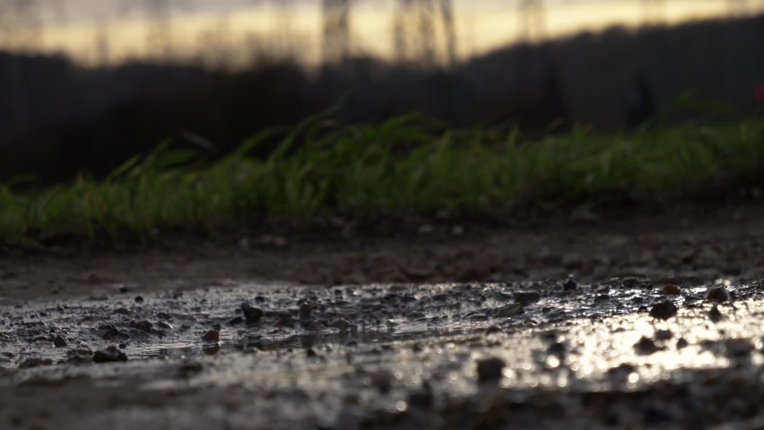 Close-up footage of stepping into puddle and splashing dirty water. Walking in black solid boots in evening. Royalty-Free Stock Footage #1075663631
