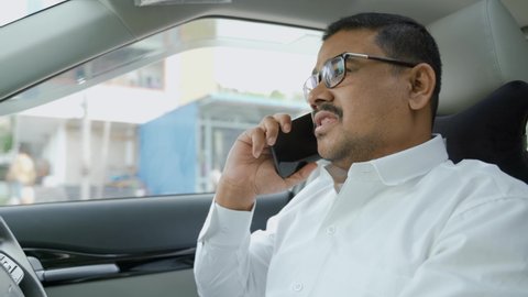 Young man talking on mobile phone while driving car - concept of safety dangerous lifestyle while driving.