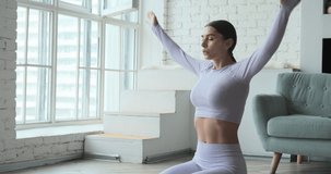 Young happy woman practicing yoga and doing breathing exercises watching live video learning classes on tablet. Female enjoying fitness pilates workout alone at home. Healthy and balanced lifestyle.