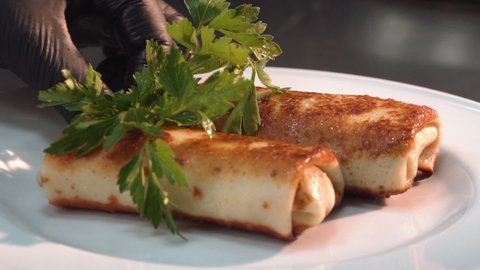 the chef decorates stuffed pancakes with parsley