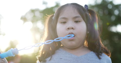 Closeup of Funny asian fat girl blows bubbles in the garden. Little asian children female playing outdoors blowing soap bubbles. Holiday and lifestyle concept.