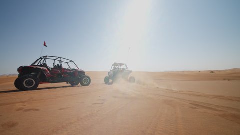 Fast sand buggy driving on the sand dunes in the desert. Outdoor motorsports activities on a fun sunny day in desert near Dubai
