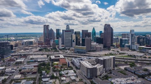 Stunning aerial hyper lapse footage of downtown area in Dallas, USA. Drone moving towards modern tall multi story commercial buildings behind rush highway in 2021