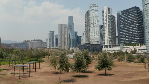 Landing footage in public park next to modern skyscrapers in Santa Fe district. Low angle view of tall buildings. Mexico City, Mexico.
