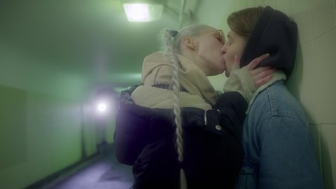 Lesbian couple of girls in love and passionately kissing on the lips of a public place of the underground passage.