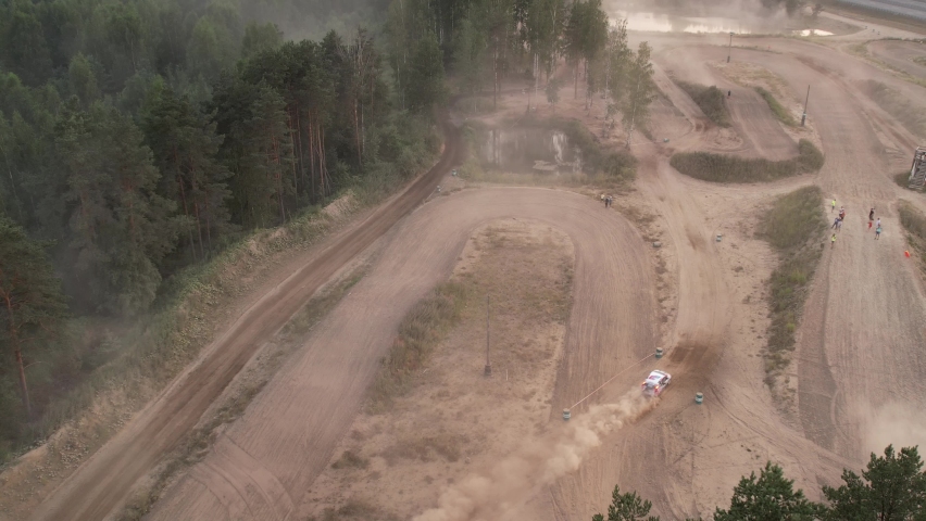 Aerial footage of a car race car driving into a drift on a dusty road.