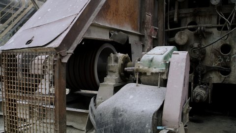 Zoom in view of motor and spinning wheel of conveyor shabby belt on quarry