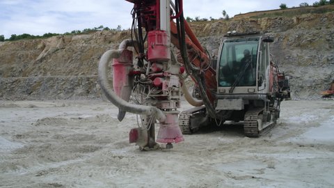 Zoom in view of shabby machine drilling rock during excavation work on quarry