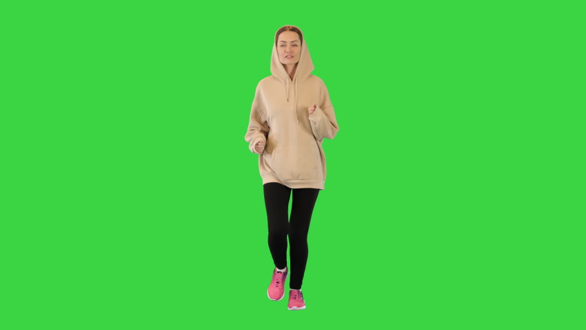 Young woman running in a hoodie running on a Green Screen, Chroma Key.