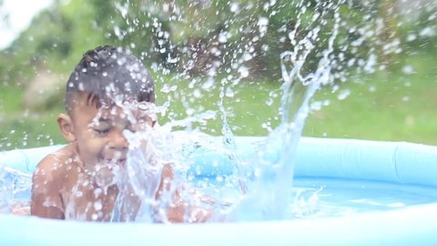 Kids having fun, playing in water in inflatable pool at home.